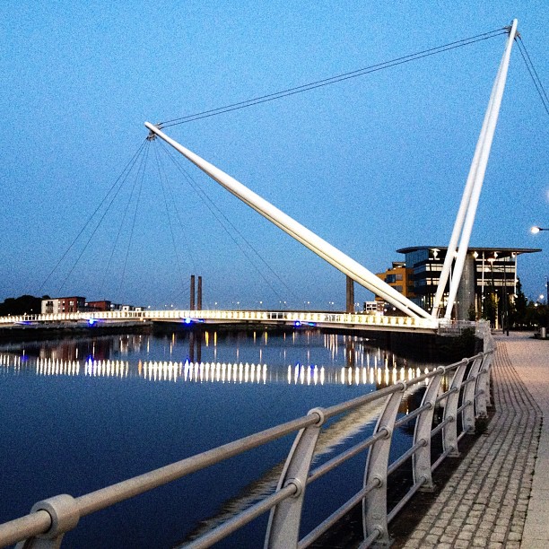 A suspended footbridge over a river lit up at night