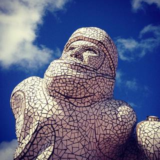 A sculture of a sailor made out of white pieces of tile against the blue sky