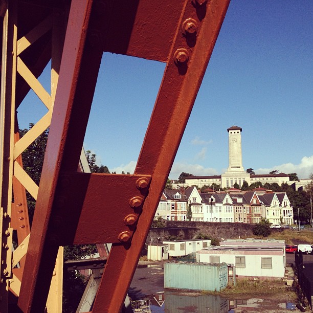 A large steel girder obstructs a view of a civic building with a row of terraced houses.