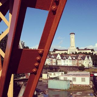 A large steel girder obstructs a view of a civic building with a row of terraced houses.