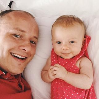 A father and child lat on the bed taking a selfie