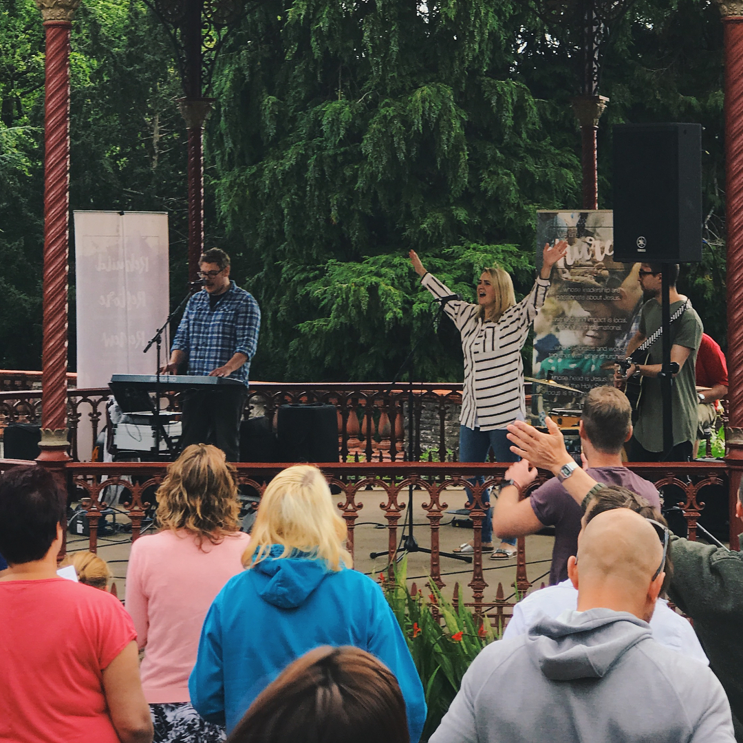 A young lady raises her arms in worship in a band stand