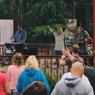 A young lady raises her arms in worship in a band stand
