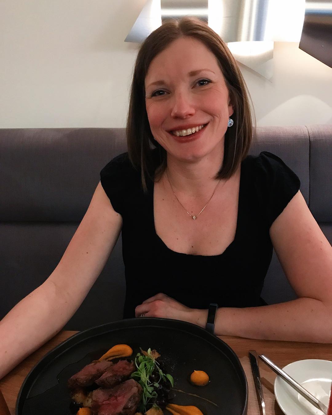 A woman sat at a restaurant table smiling