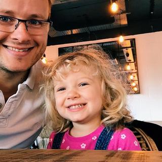 A father and his daughter take a selfie in a coffee shop. 