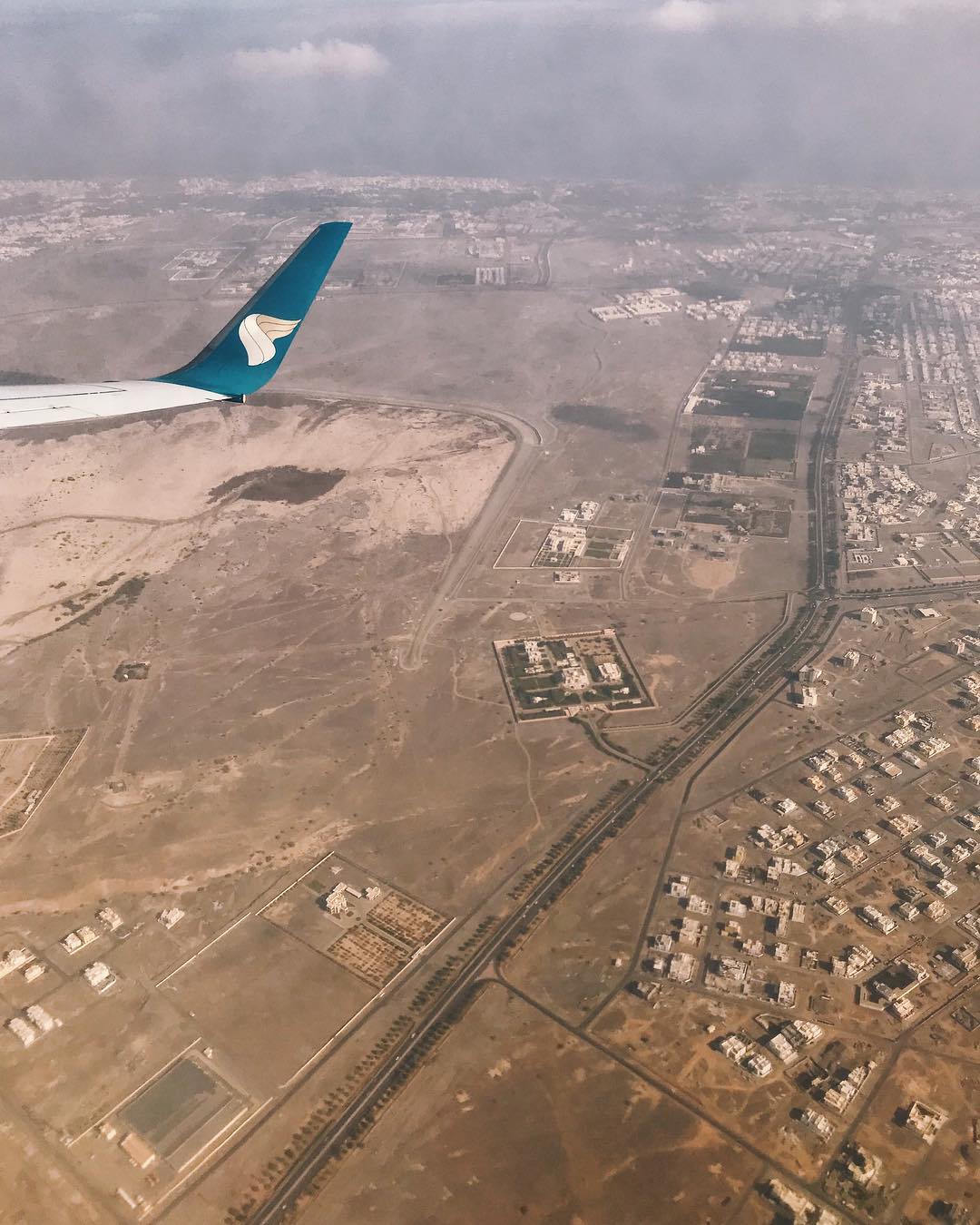 An aerial view of Oman from a plane showing buildings and large expanses of brown land