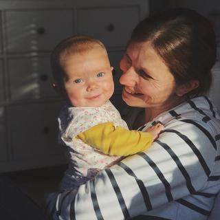 A mother in a stripy top holding a small baby
