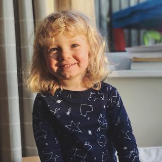 A small girl sat on a stool smiling