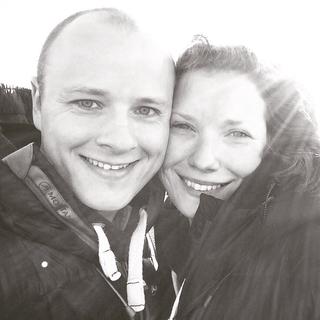 A man and a woman smiling with their cheeks together