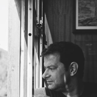 A man sat down looking out of the train window.