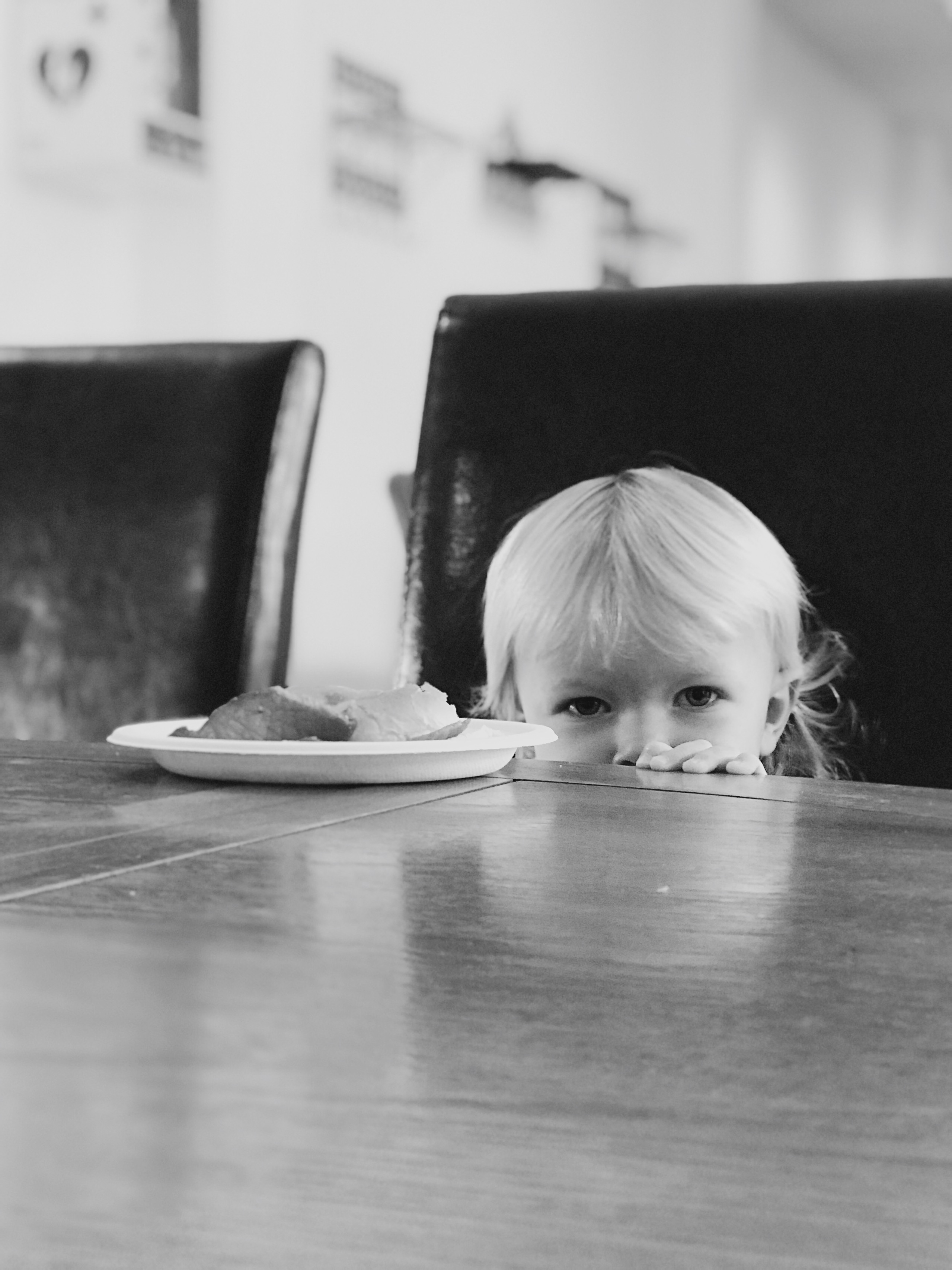 A little girls head at eye level of a table looking at the camera.