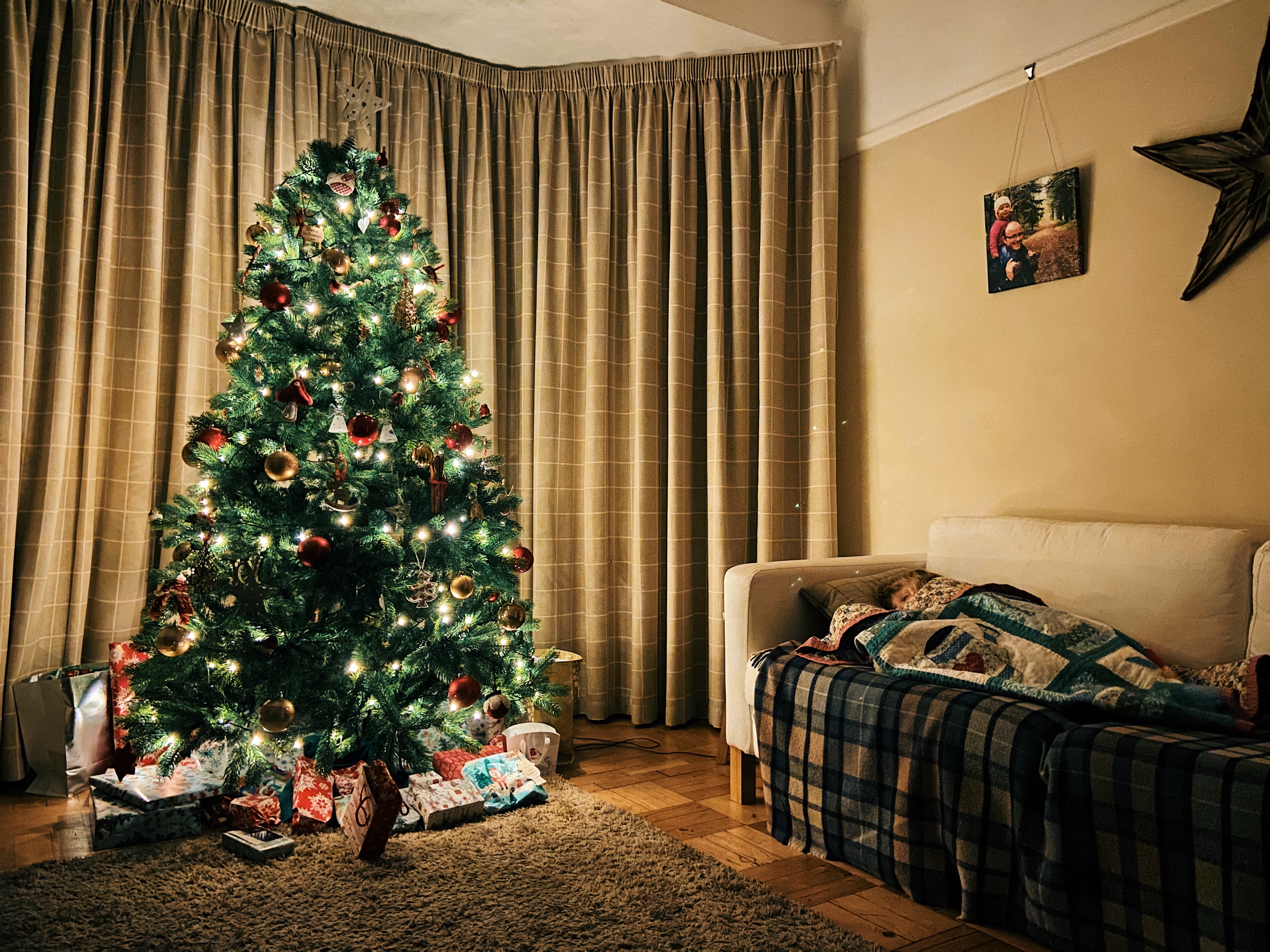 Little girl laying on a sofa with a Christmas tree lit up