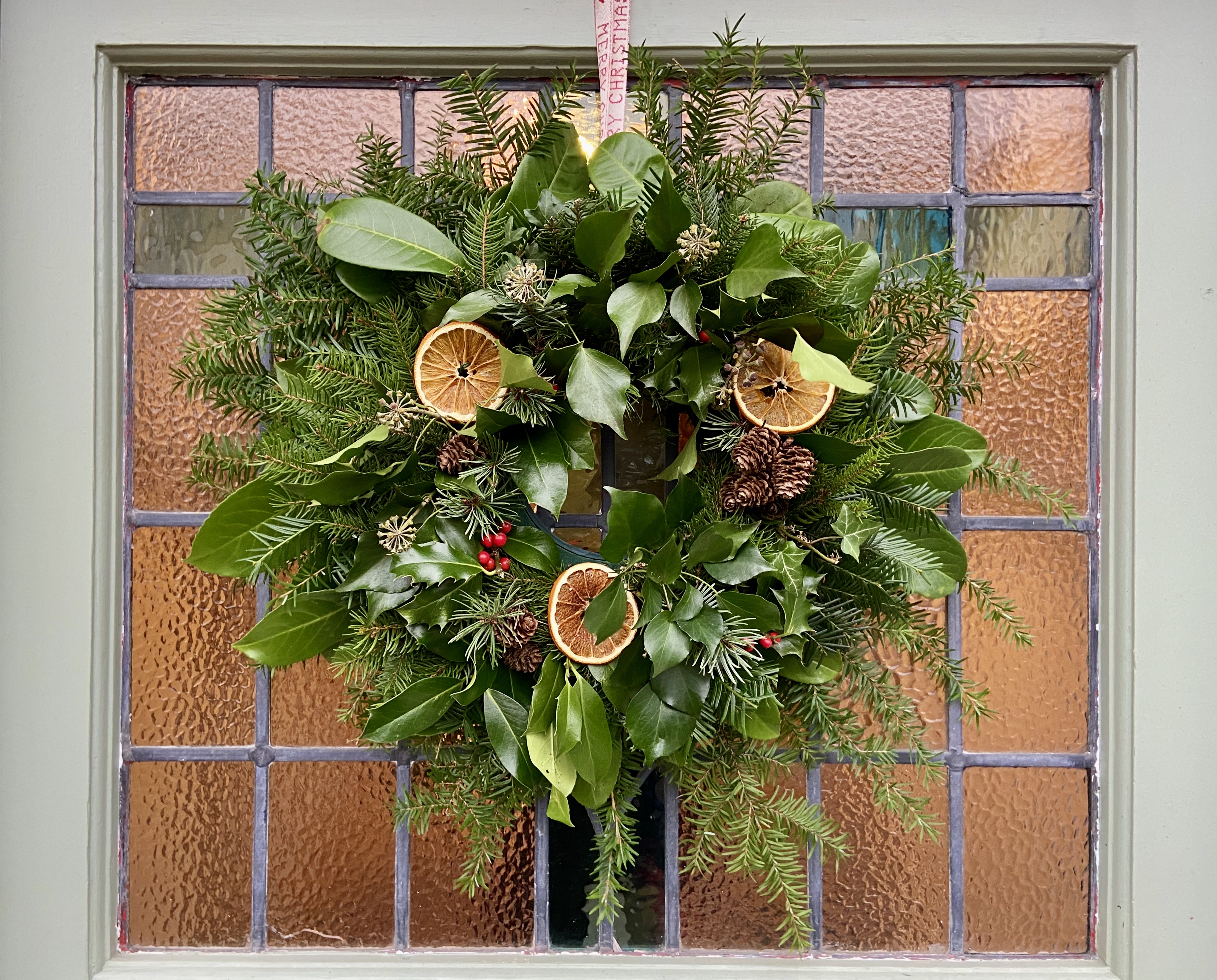 A wreath on the stained glass of a front door. 