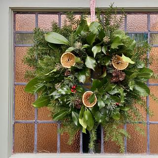 A wreath on the stained glass of a front door. 