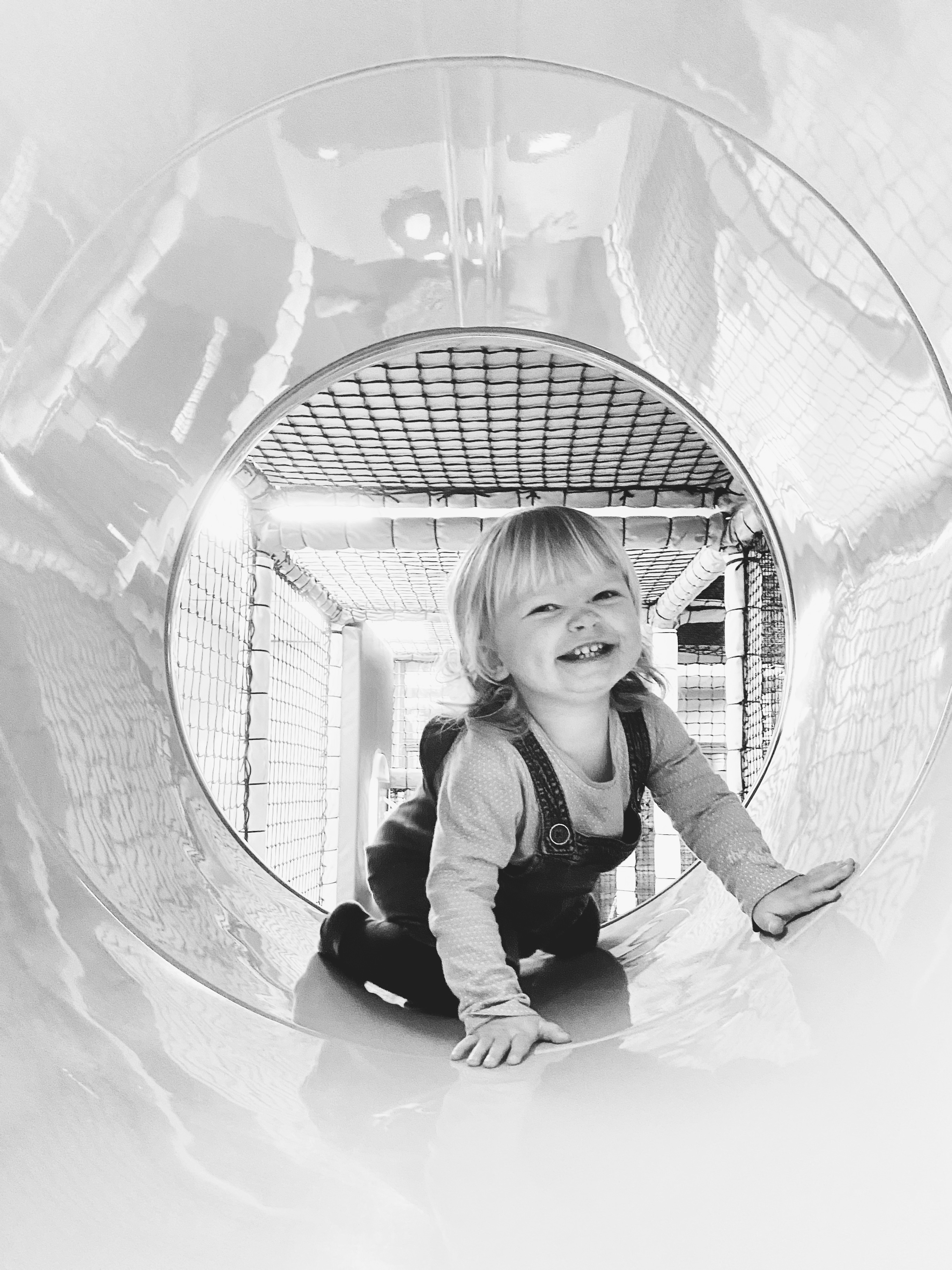A little girl smiling in a soft play tunnel 